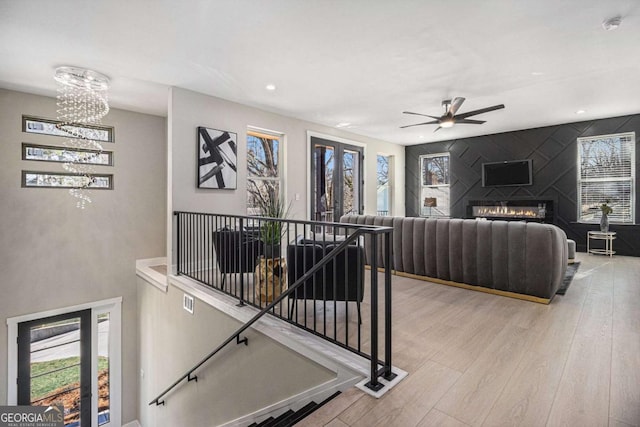 living area with plenty of natural light, a glass covered fireplace, and light wood-style flooring