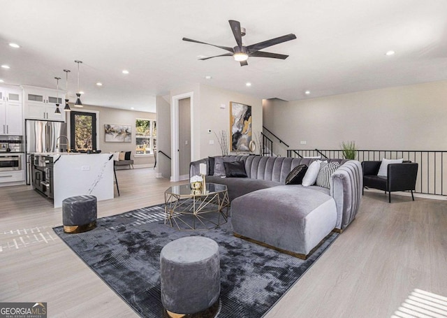 living area with light wood-type flooring, a ceiling fan, and recessed lighting