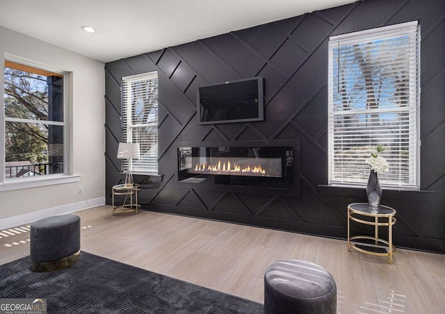 living room featuring recessed lighting, baseboards, wood finished floors, and a glass covered fireplace