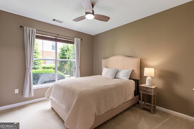 bedroom featuring a textured ceiling, carpet flooring, visible vents, and baseboards