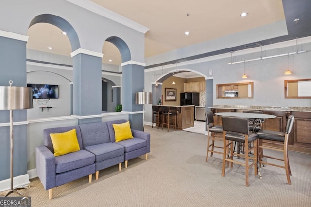 living room featuring arched walkways, recessed lighting, ornamental molding, light carpet, and baseboards