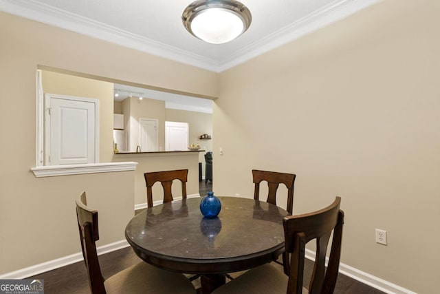 dining space featuring dark wood-style floors, baseboards, and crown molding