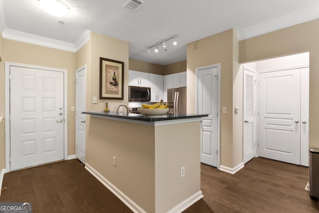 kitchen featuring visible vents, dark countertops, dark wood-style flooring, a peninsula, and stainless steel appliances