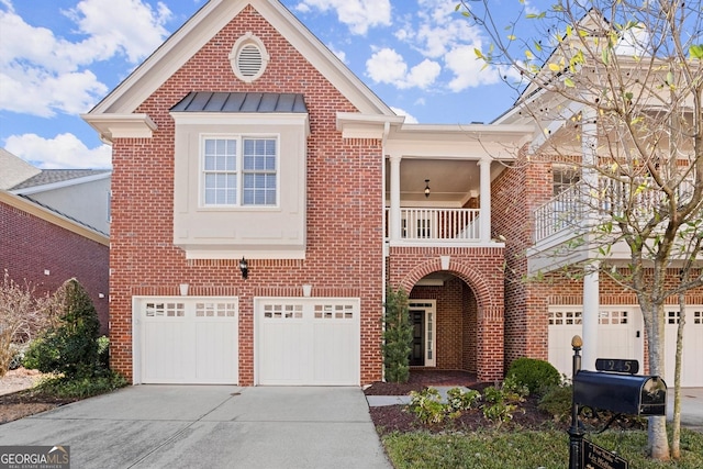 view of front of property with a garage, concrete driveway, a balcony, a standing seam roof, and brick siding