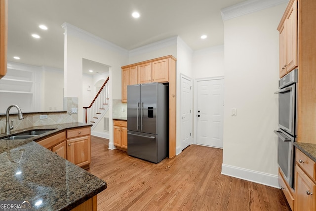 kitchen with stainless steel appliances, ornamental molding, a sink, and light wood-style floors