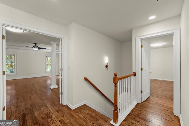 hall featuring baseboards, decorative columns, an upstairs landing, and wood finished floors