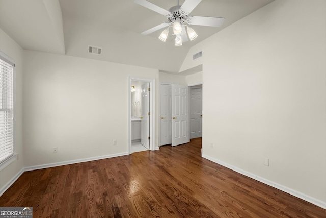 unfurnished bedroom featuring lofted ceiling, multiple windows, visible vents, and wood finished floors