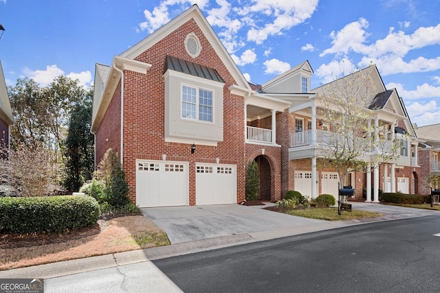 view of front of property featuring metal roof, an attached garage, brick siding, concrete driveway, and a standing seam roof