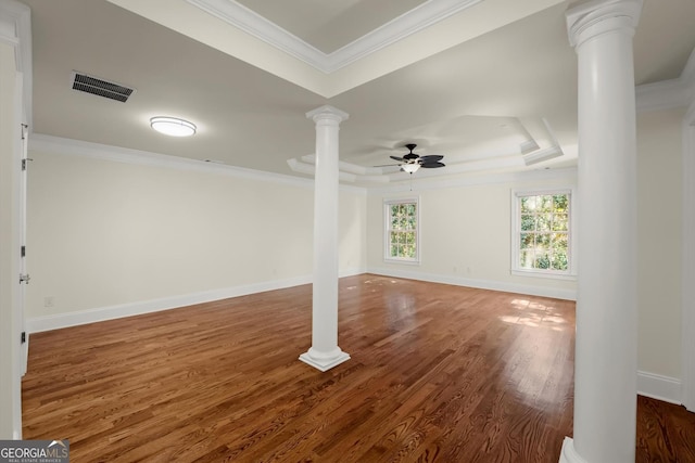 unfurnished room with decorative columns, visible vents, wood finished floors, a tray ceiling, and crown molding