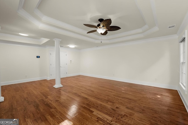 unfurnished room featuring a tray ceiling, decorative columns, a ceiling fan, wood finished floors, and baseboards