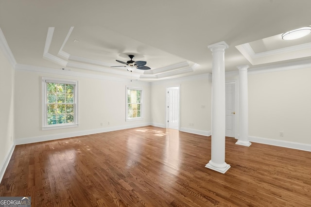 unfurnished living room with a ceiling fan, ornamental molding, wood finished floors, a tray ceiling, and ornate columns