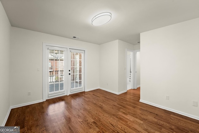 spare room featuring baseboards, visible vents, and wood finished floors