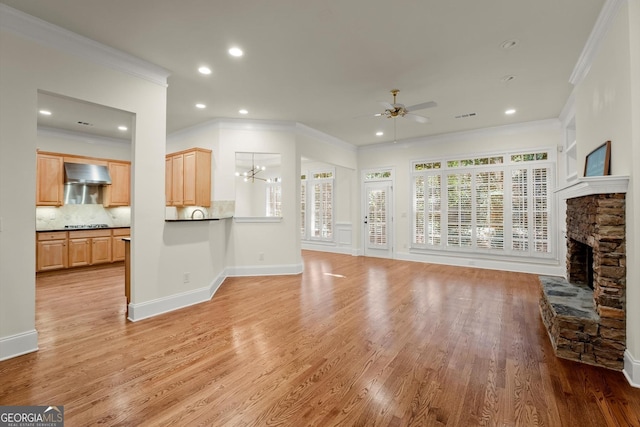 living area featuring a fireplace, light wood-style floors, ornamental molding, baseboards, and ceiling fan with notable chandelier