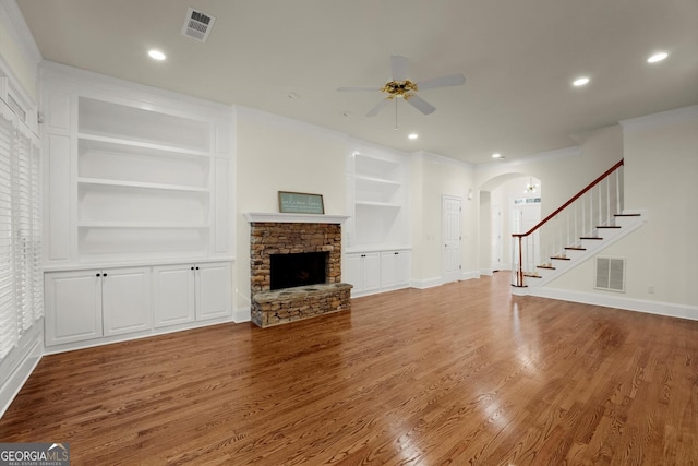 unfurnished living room featuring built in features, visible vents, a fireplace, and stairs