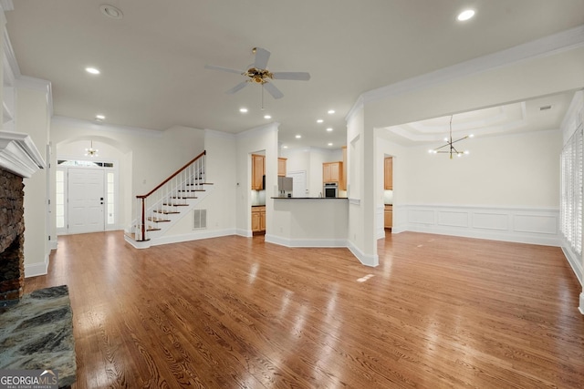 unfurnished living room featuring recessed lighting, light wood-style floors, ornamental molding, stairway, and wainscoting