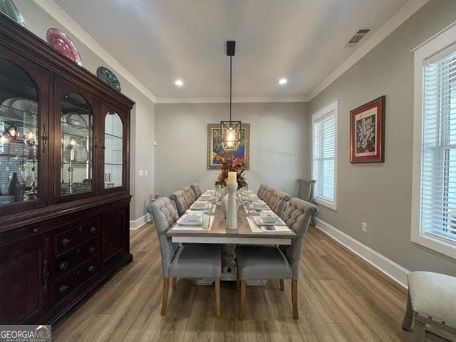 dining room featuring ornamental molding, light wood-style flooring, and baseboards