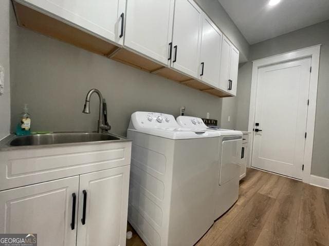 washroom featuring light wood-style floors, cabinet space, a sink, and separate washer and dryer