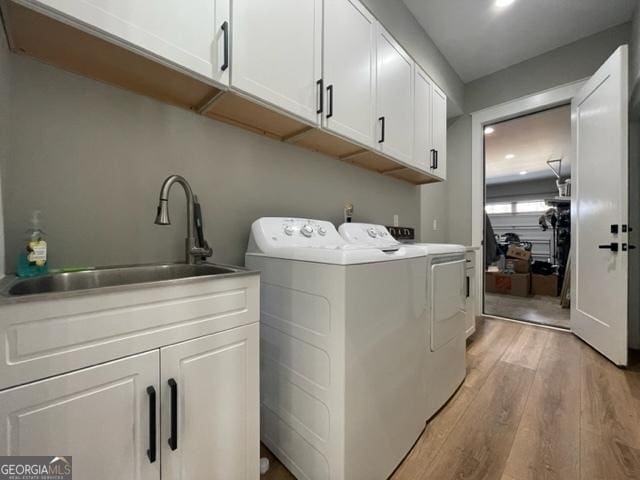 laundry area featuring light wood-style flooring, recessed lighting, separate washer and dryer, a sink, and cabinet space