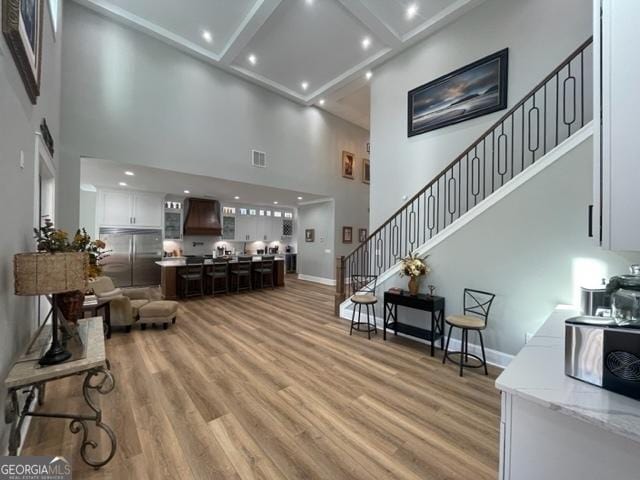 living room with stairs, light wood finished floors, visible vents, and baseboards