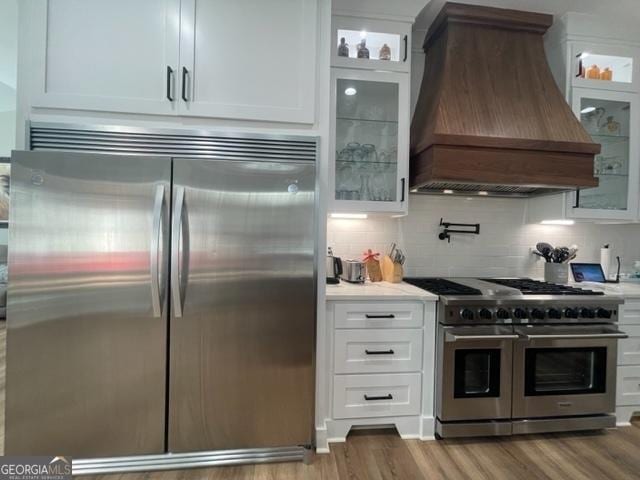 kitchen featuring stainless steel appliances, light countertops, custom range hood, decorative backsplash, and white cabinets