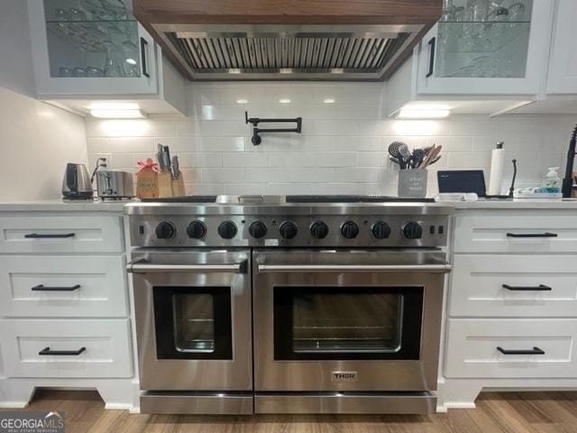 kitchen featuring white cabinets, glass insert cabinets, range with two ovens, and ventilation hood