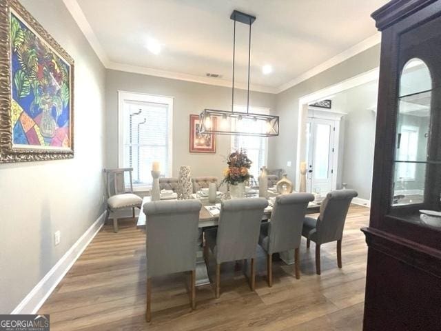 dining room featuring ornamental molding, plenty of natural light, wood finished floors, and baseboards