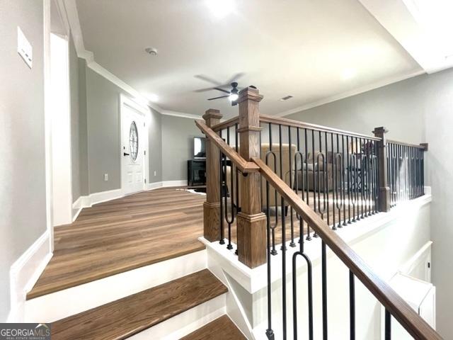 staircase with ornamental molding, ceiling fan, baseboards, and wood finished floors