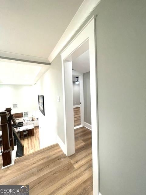 hall featuring ornamental molding, light wood-style flooring, and baseboards