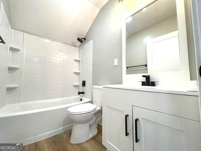 bathroom with lofted ceiling, shower / bathing tub combination, toilet, vanity, and wood finished floors