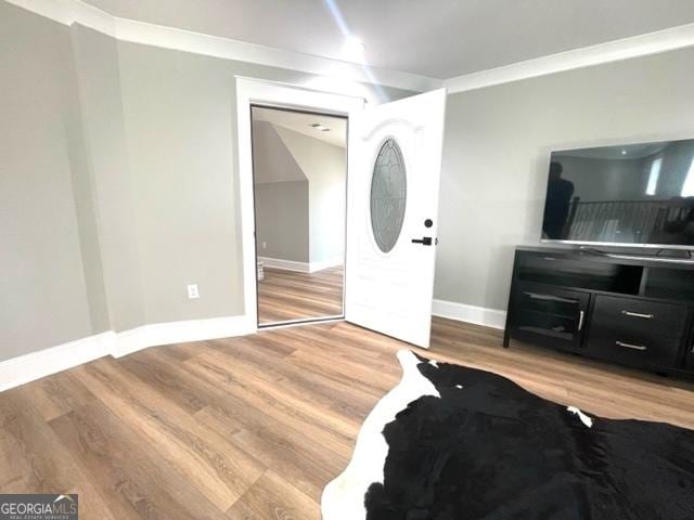 foyer with ornamental molding, baseboards, and wood finished floors