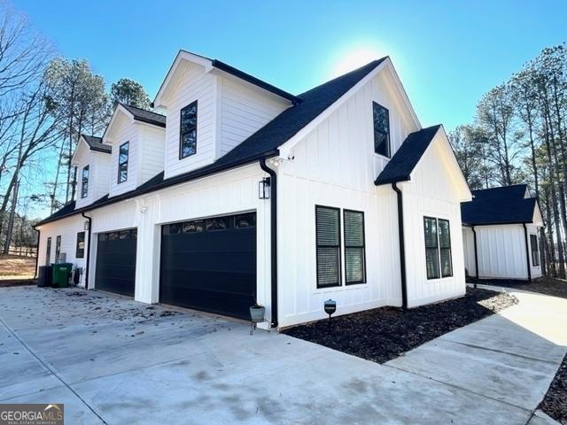 view of property exterior with board and batten siding, driveway, and an attached garage