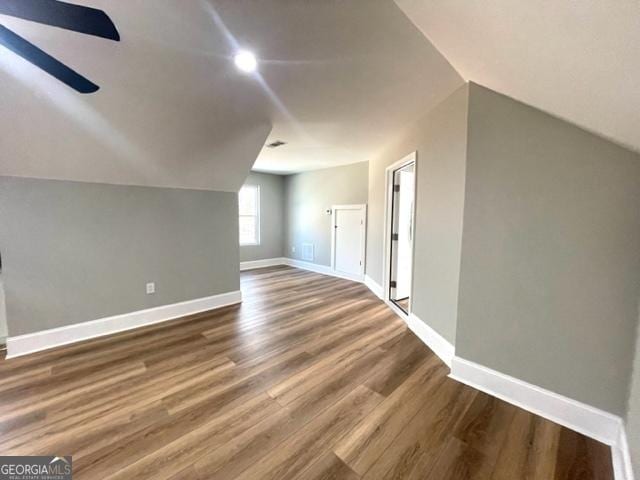 bonus room with vaulted ceiling, dark wood finished floors, a ceiling fan, and baseboards