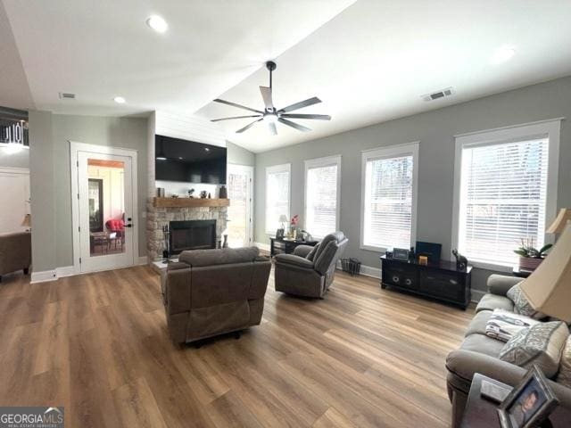 living room featuring a fireplace, visible vents, a ceiling fan, and wood finished floors