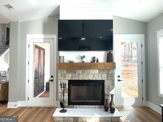 living room featuring lofted ceiling, plenty of natural light, visible vents, and wood finished floors