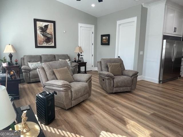 living room with vaulted ceiling, wood finished floors, and baseboards