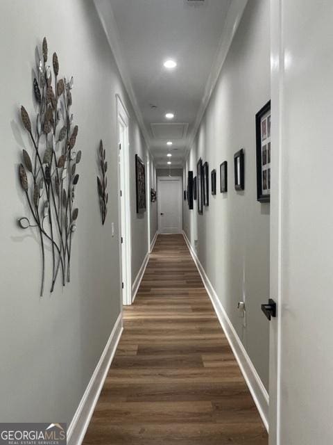 hall with dark wood-style flooring, recessed lighting, ornamental molding, attic access, and baseboards