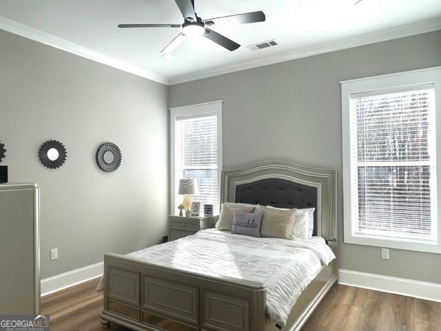 bedroom featuring visible vents, dark wood finished floors, and crown molding