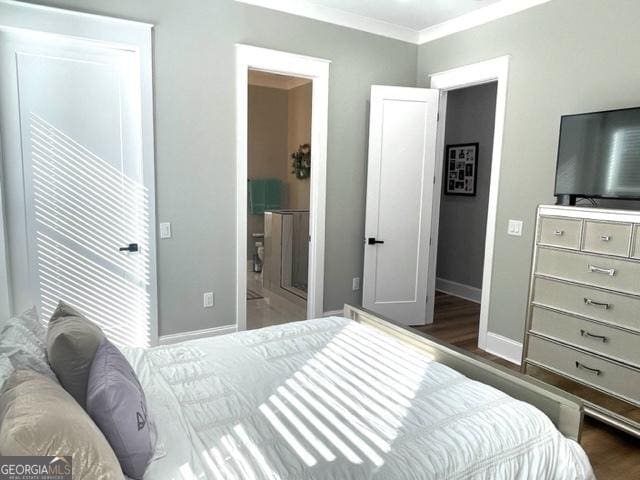 bedroom featuring ensuite bathroom, ornamental molding, wood finished floors, and baseboards