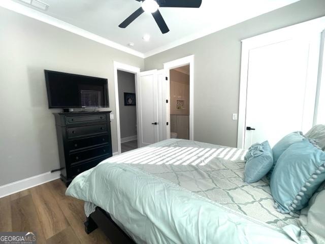 bedroom with crown molding, baseboards, ceiling fan, and wood finished floors