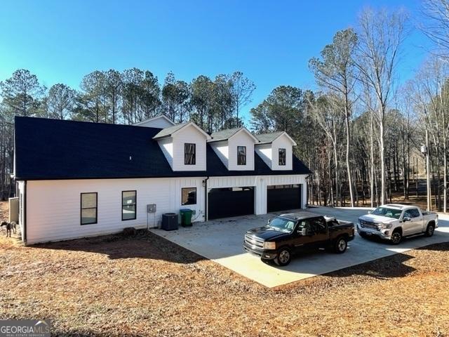 view of front facade featuring driveway, an attached garage, and cooling unit