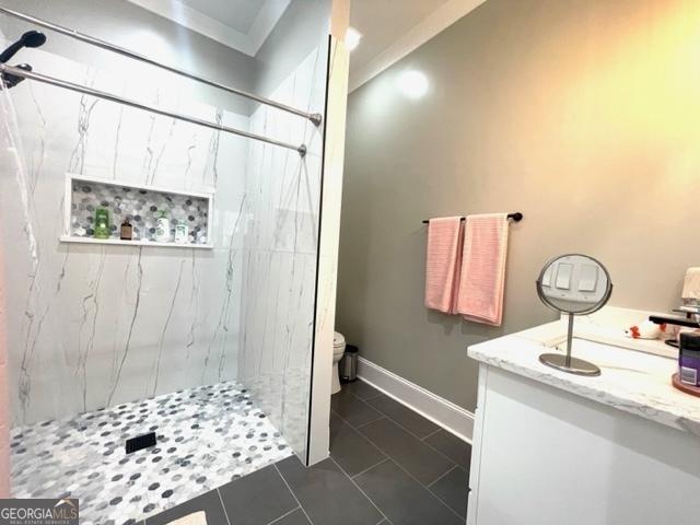 full bathroom featuring a marble finish shower, toilet, vanity, baseboards, and tile patterned floors