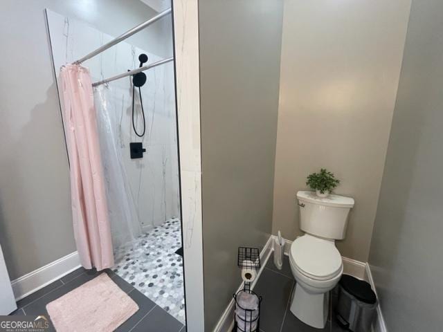 full bathroom featuring a shower with shower curtain, tile patterned floors, toilet, and baseboards