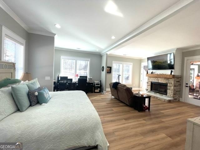 bedroom with a fireplace, ornamental molding, wood finished floors, and multiple windows