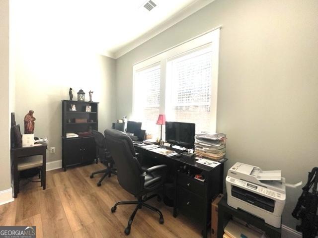 home office featuring visible vents, crown molding, baseboards, and wood finished floors