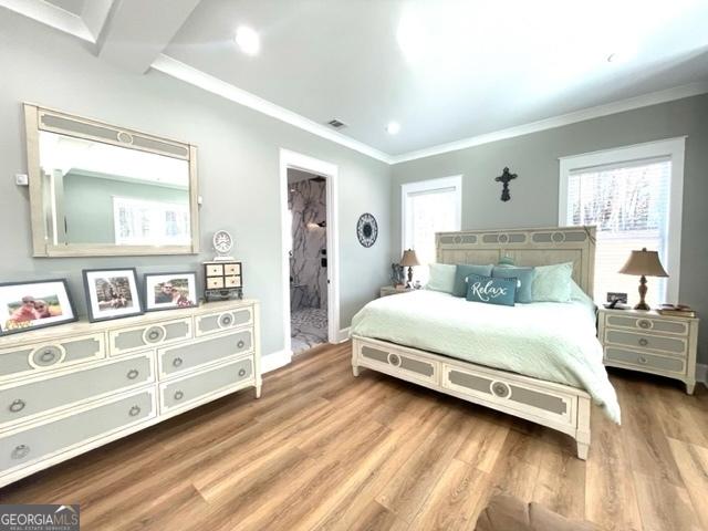 bedroom with ornamental molding, multiple windows, and wood finished floors