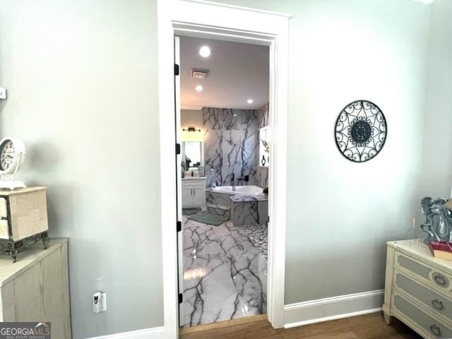 hallway featuring baseboards, wood finished floors, and recessed lighting