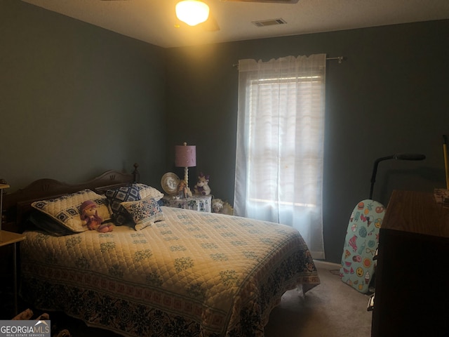 bedroom featuring a ceiling fan, multiple windows, visible vents, and carpet flooring