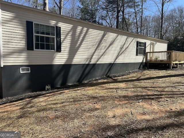 view of side of home with crawl space and a deck