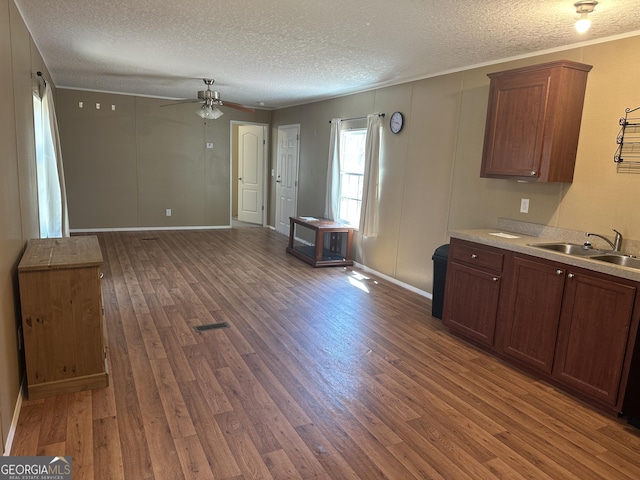 kitchen with a ceiling fan, wood finished floors, light countertops, a textured ceiling, and a sink