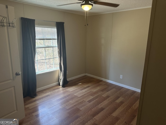 empty room with ceiling fan, a textured ceiling, baseboards, and wood finished floors